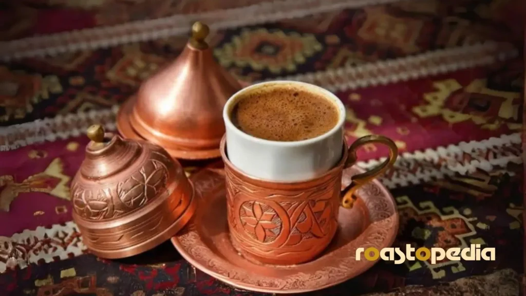 Osmanli kahvesi coffee in a metalic cup on a table covered by a carpet.